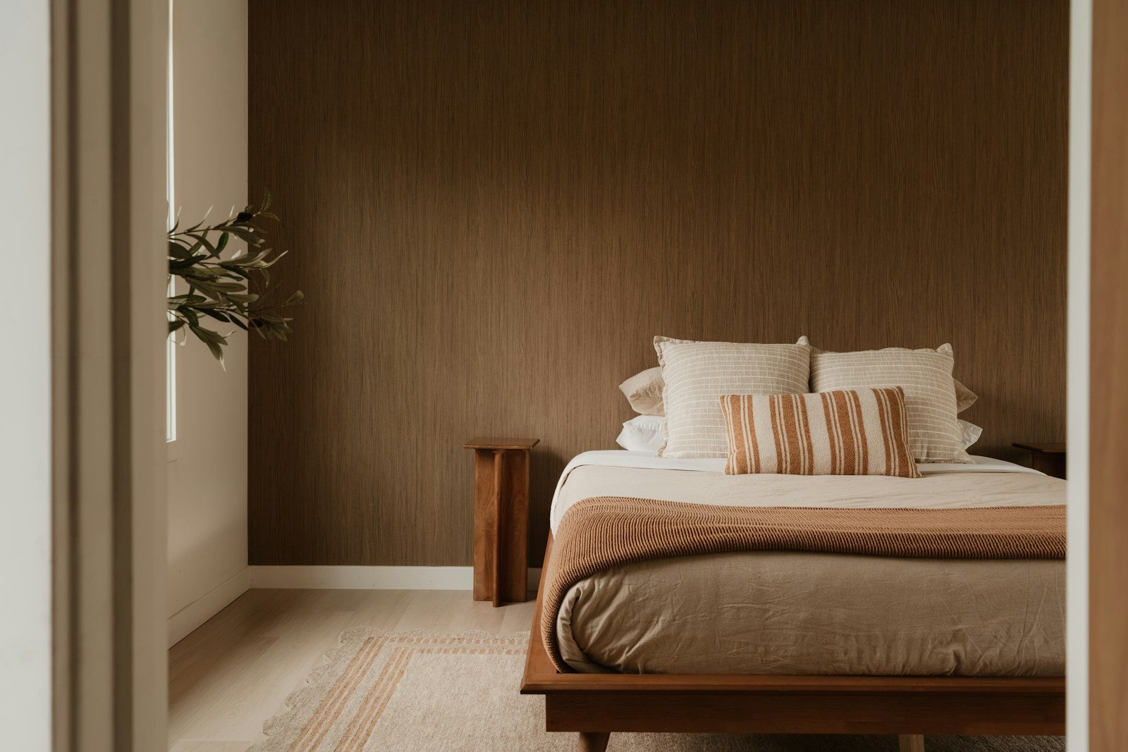 Photo by Clay Banks Modern bedroom with bed, pillows, and warm brown wall